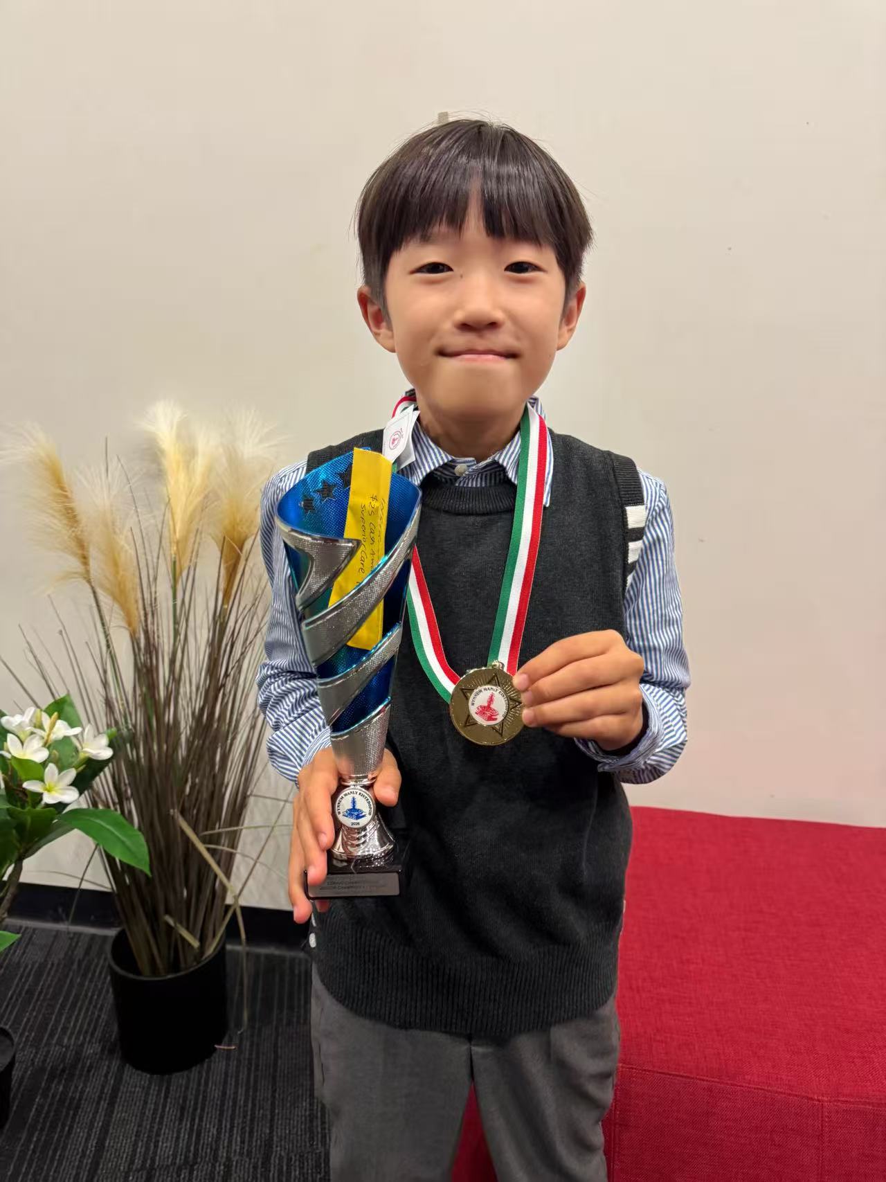 Raphael Feng holding his first trophy and medal from Wynnum Manly Junior