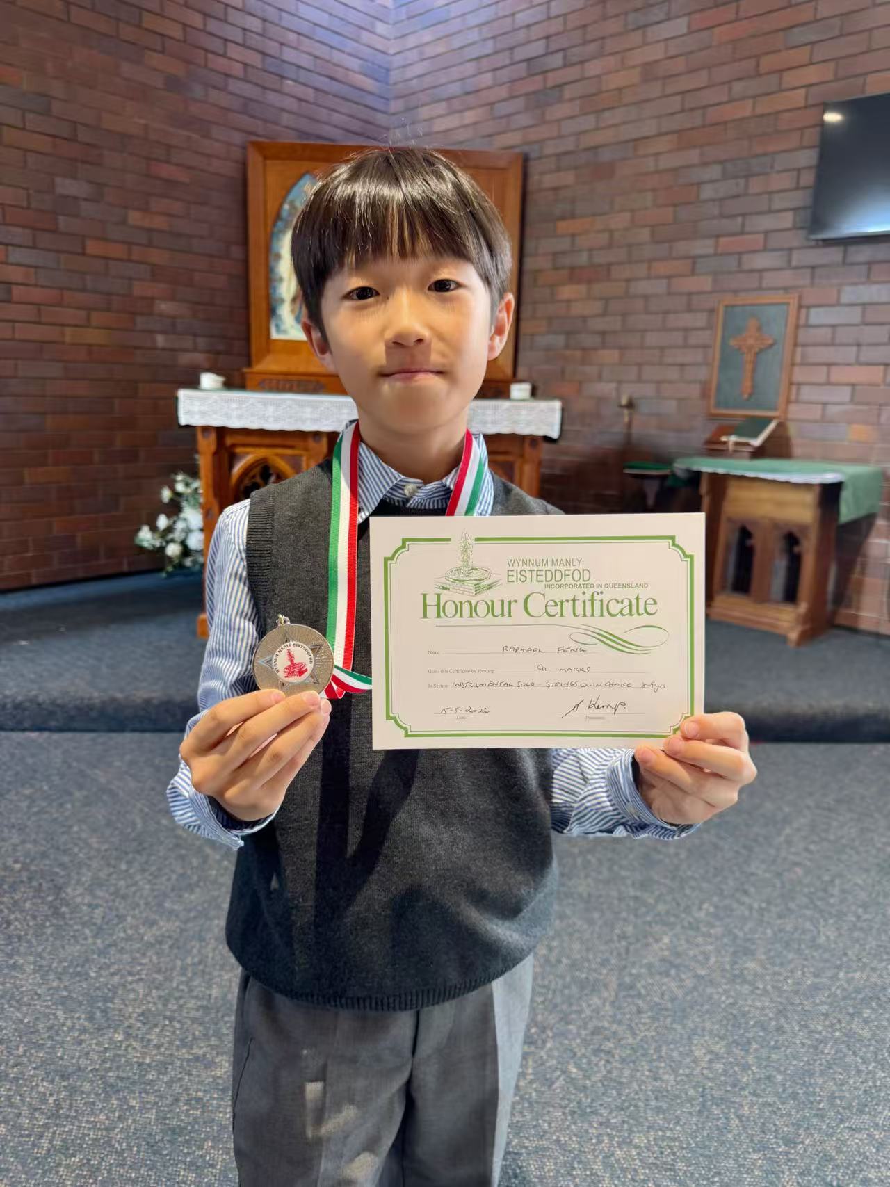 Raphael Feng holding a medal and honour certificate from Wynnum Manly String Eisteddfod