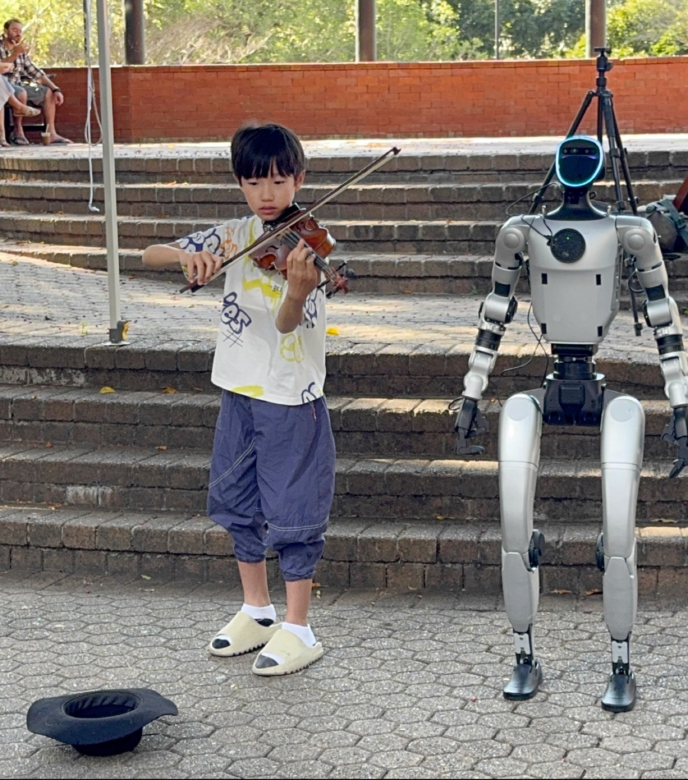 Raphael Feng performing violin next to a robot