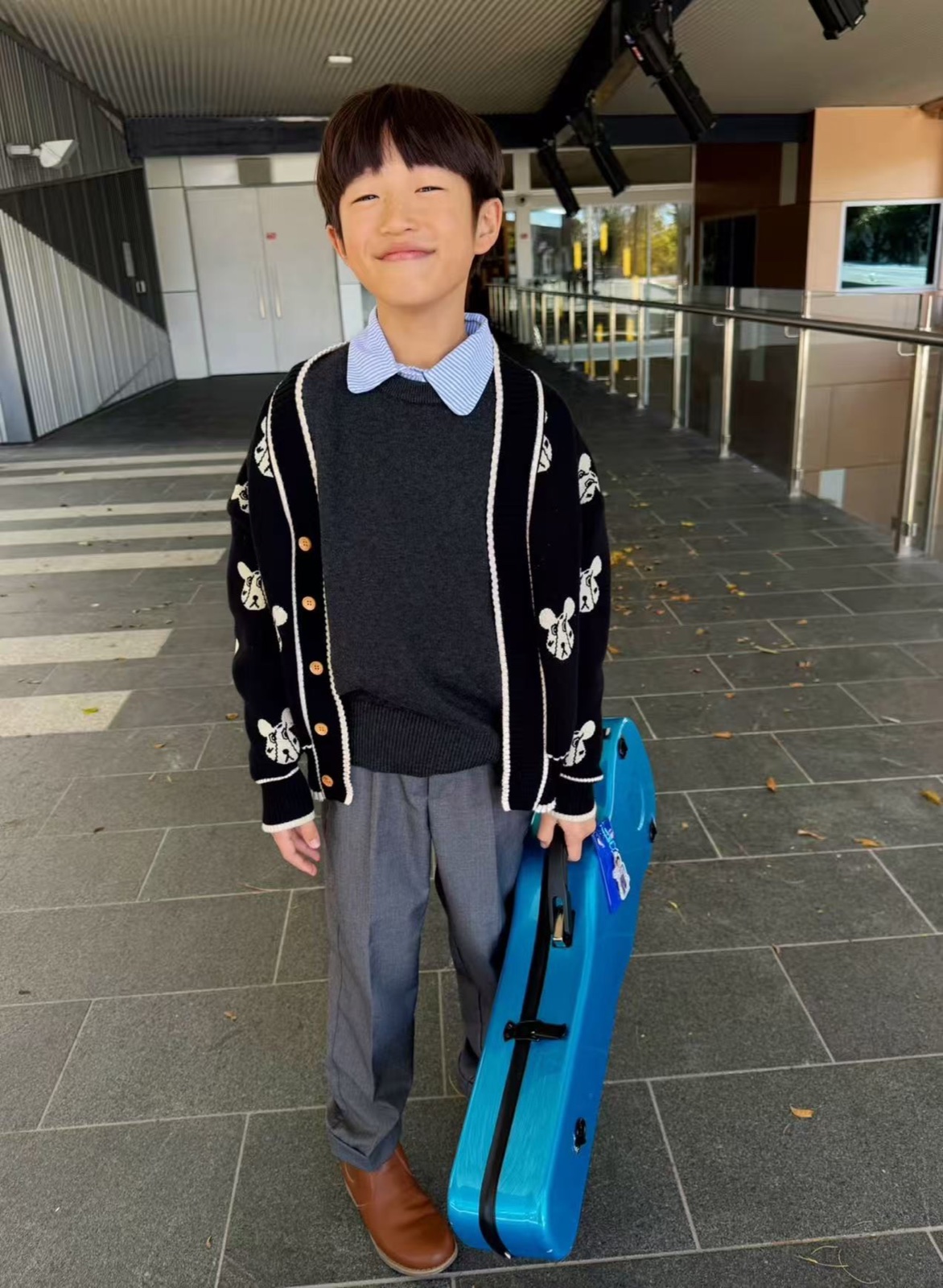 Raphael Feng smiling with his violin case